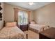 Comfortable bedroom with two twin beds, neutral walls, ceiling fan, window with shutters, and wood dressers at 5036 Brickell Park Cv, Bradenton, FL 34211