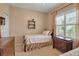 Neutral bedroom featuring a twin bed, wood furnishings, a window with shutters, and a wall-mounted display shelf at 5036 Brickell Park Cv, Bradenton, FL 34211