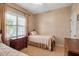 A quaint neutral bedroom featuring a twin bed, wood furnishings, and a bright window with wooden shutters at 5036 Brickell Park Cv, Bradenton, FL 34211