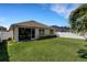 A backyard with green grass, a white fence, and a covered screened porch with a home's exterior at 5111 11Th E St, Bradenton, FL 34203