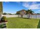 Green backyard with a white fence, palm trees, and well manicured garden with a blue sky overhead at 5111 11Th E St, Bradenton, FL 34203