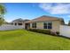 View of backyard with white fence, green grass, and a beige home with brown trim and windows at 5111 11Th E St, Bradenton, FL 34203