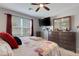 Bedroom with neutral walls, red curtains, and a dresser, illuminated by a ceiling fan and natural light at 5111 11Th E St, Bradenton, FL 34203