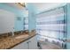 Bathroom with blue walls, granite countertops, a sink, toilet, and a shower with a striped curtain at 5623 Wilde Oak Way, Sarasota, FL 34232