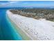 Breathtaking aerial view of a bustling beach with turquoise water and nearby buildings and homes at 5729 Garden Lakes Palm, Bradenton, FL 34203