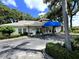 Well maintained single story building featuring a blue awning, decorative brick columns, and manicured landscaping at 5810 Garden Lakes Palm, Bradenton, FL 34203