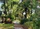 A peaceful walkway meanders through lush greenery and mature trees, creating a serene outdoor space at 5810 Garden Lakes Palm, Bradenton, FL 34203