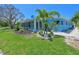 Bright blue single-story house with well-manicured lawn and mature palm trees in a tropical setting at 5920 Gulf Of Mexico Dr, Longboat Key, FL 34228