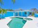 Backyard oasis featuring a sparkling pool and spa, complemented by the home's vibrant blue exterior at 5920 Gulf Of Mexico Dr, Longboat Key, FL 34228