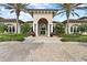 Stunning exterior of clubhouse entrance featuring an arched entryway, columns, and manicured landscaping with beautiful plants at 5987 Snowy Egret Dr, Sarasota, FL 34238