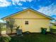 View of back exterior showing maintained yellow exterior and the lawn area under a partly cloudy sky at 6113 Mckee St, Port Charlotte, FL 33981
