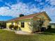 This property features a well-maintained lawn and garden and a yellow exterior under a partly cloudy sky at 6113 Mckee St, Port Charlotte, FL 33981