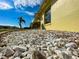 This property features a well-maintained rock garden, window and yellow exterior under a partly cloudy sky at 6113 Mckee St, Port Charlotte, FL 33981