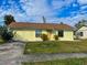 Charming single-story home with a yellow exterior, well-maintained lawn and a brown roof under a partly cloudy sky at 6113 Mckee St, Port Charlotte, FL 33981