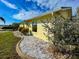 This property features a well-maintained rock garden, window and yellow exterior under a partly cloudy sky at 6113 Mckee St, Port Charlotte, FL 33981