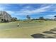 Scenic golf course view with golfers putting on a green near a tranquil lake, showcasing the beautiful landscape at 6519 Grand Estuary Trl # 107, Bradenton, FL 34212
