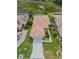 Overhead view of a tile roofed home with lush landscaping, a pond, and a large driveway at 6764 Hickory Hammock Cir, Bradenton, FL 34202
