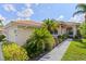 Inviting front entrance with well-manicured bushes and palm trees, arched doorway, and neutral colored siding at 6764 Hickory Hammock Cir, Bradenton, FL 34202