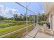 Exterior shot of a screened lanai with a clear view of the green lawn and surrounding trees at 6764 Hickory Hammock Cir, Bradenton, FL 34202