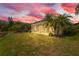Evening view of a screened-in patio surrounded by tropical palm trees and a tranquil green lawn at 6764 Hickory Hammock Cir, Bradenton, FL 34202