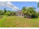 Relaxing screened-in patio surrounded by tropical palm trees and a tranquil green lawn and pond at 6764 Hickory Hammock Cir, Bradenton, FL 34202