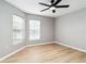 Empty bedroom with two bright windows, ceiling fan, and light wood flooring at 7 Arbor Oaks Dr, Sarasota, FL 34232