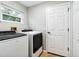 Well-equipped laundry room with a window, washer, dryer, and storage shelves at 7 Arbor Oaks Dr, Sarasota, FL 34232