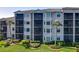 Exterior of a condo building with screened lanais surrounded by a lush, green lawn at 7005 River Hammock Dr # 206, Bradenton, FL 34212