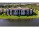 Exterior view of the condo building overlooking a serene lake and landscaped grounds at 7005 River Hammock Dr # 206, Bradenton, FL 34212