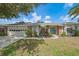 Charming home featuring a blue front door, well-manicured lawn, and beautiful landscaping with plenty of foliage at 7984 Glenbrooke Ln, Sarasota, FL 34243