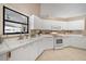 Bright kitchen boasts white cabinets, drawers, tile floor, ample countertops, and a black framed window at 7984 Glenbrooke Ln, Sarasota, FL 34243