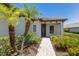 Charming home entrance with tile roof, paver walkway, lush landscaping, and palm trees at 8191 Gabanna Dr, Sarasota, FL 34231