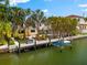 Waterfront property featuring a private dock, boat lift, lush tropical landscaping, and direct water access at 868 Siesta Key Cir, Sarasota, FL 34242