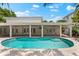 A luxurious backyard featuring a kidney-shaped pool with an expansive patio, multiple doors to the home at 868 Siesta Key Cir, Sarasota, FL 34242