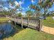 Scenic view of a community pond with a wooden bridge, lush trees, and manicured green lawn at 911 Cimarron Cir, Bradenton, FL 34209