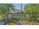 The Villa D'Este community entrance boasts lush landscaping and beautiful palms under a sunny sky at 4517 Las Brisas Ln, Sarasota, FL 34238