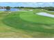 Beautiful golf course featuring a green with a flag, a nearby sand trap, and a tranquil lake in the background at 4517 Las Brisas Ln, Sarasota, FL 34238