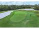 Aerial view of a green on a stunning golf course, complete with lush trees, a nearby lake, and fine sand at 4517 Las Brisas Ln, Sarasota, FL 34238