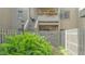Close-up of a condo entrance with a wooden fence, lush ferns, and a stairway to upper units at 107 Woodland Pl # 107, Osprey, FL 34229