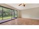 Living room with tiled floor and a screened lanai offering a view of lush greenery at 107 Woodland Pl # 107, Osprey, FL 34229
