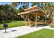 Community pavilion featuring a picnic table and grill amidst lush greenery, perfect for outdoor gatherings at 107 Woodland Pl # 107, Osprey, FL 34229