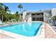 Large, sparkling pool area surrounded by lounge chairs, mature landscaping, and a well-maintained building at 107 Woodland Pl # 107, Osprey, FL 34229