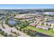 Aerial view showcases a community with a pond, lush greenery, houses, and surrounding amenities like a school at 11507 84Th Street E Cir # 102, Parrish, FL 34219