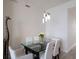 A dining area with a glass-top table, white chairs, and unique light fixture at 1155 N Gulfstream Ave # 406, Sarasota, FL 34236