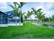 A side yard view shows tropical landscaping with palm trees, green lawn, and the screened-in lanai at 117 Marker Rd, Rotonda West, FL 33947