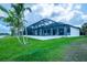 Exterior view of the home's screened lanai, overlooking the lush green lawn and canal at 117 Marker Rd, Rotonda West, FL 33947