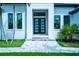 Contemporary home featuring a modern glass front door, with tiled entrance and lush landscaping at 117 Marker Rd, Rotonda West, FL 33947