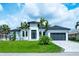 Beautiful modern home with lush lawn, palm trees, dark roof, and paver driveway at 117 Marker Rd, Rotonda West, FL 33947