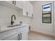 Bright laundry room boasts white cabinetry, black hardware, and a modern black faucet at 117 Marker Rd, Rotonda West, FL 33947