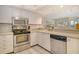 Modern kitchen with stainless steel appliances, white cabinetry, and views into the dining and living areas at 1226 Siesta Bayside Dr # 1226C, Sarasota, FL 34242